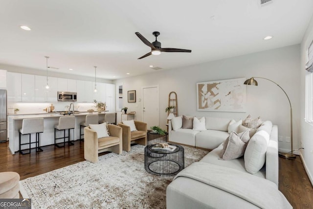 living area featuring dark wood finished floors, a ceiling fan, and recessed lighting