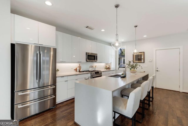 kitchen featuring stainless steel appliances, a sink, visible vents, a kitchen bar, and decorative backsplash