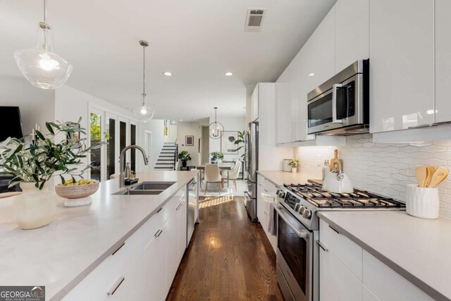 kitchen with a sink, light countertops, white cabinets, appliances with stainless steel finishes, and visible vents