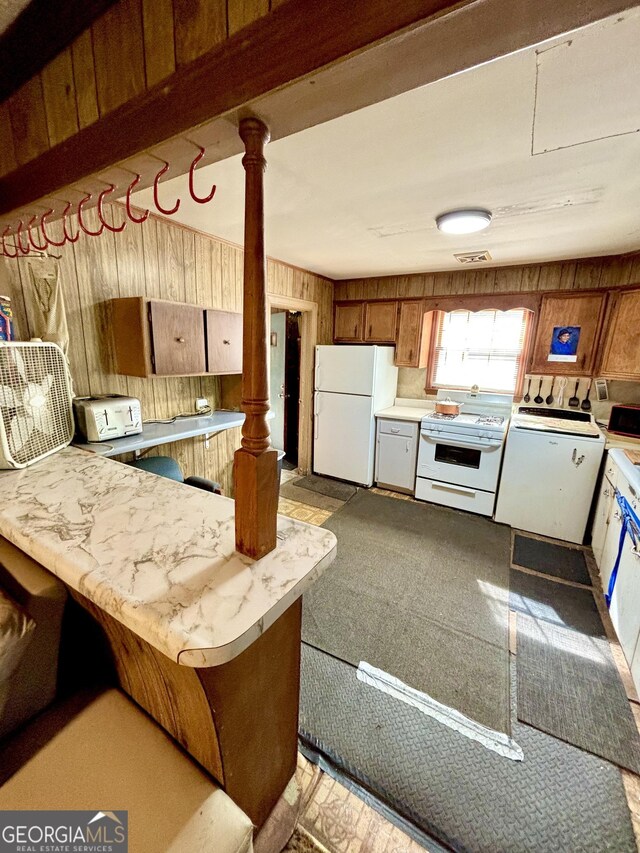 165 Vine St, Athens, GA 30601 - kitchen featuring white appliances, washer / dryer, light countertops, a peninsula, and wood walls