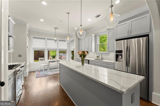kitchen featuring visible vents, a sink, appliances with stainless steel finishes, and ornamental molding