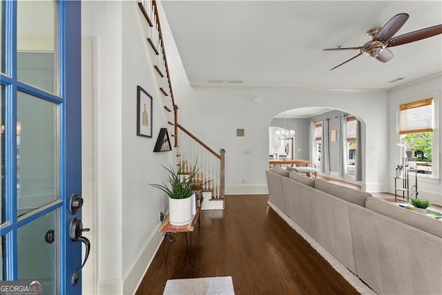 entryway featuring baseboards, stairway, dark wood-type flooring, arched walkways, and ceiling fan with notable chandelier