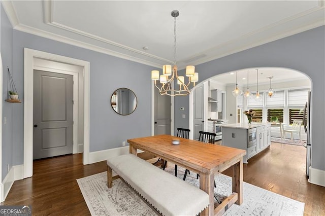 dining area featuring arched walkways, ornamental molding, and baseboards