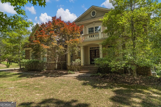 view of front of home featuring a porch, a garage, brick siding, a balcony, and stucco siding
