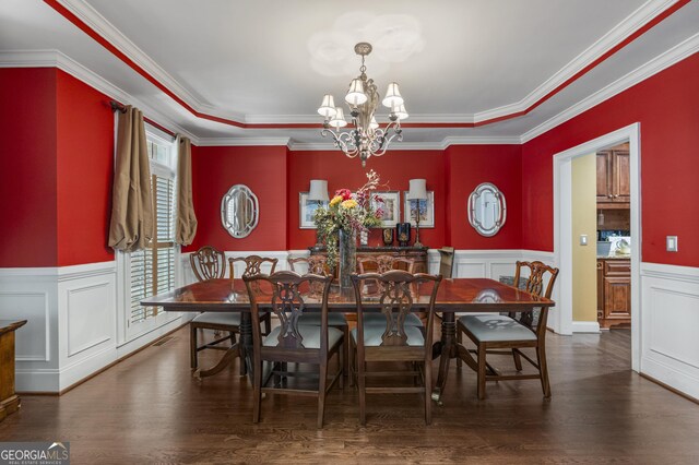 dining area with a chandelier, ornamental molding, wood finished floors, and a wainscoted wall