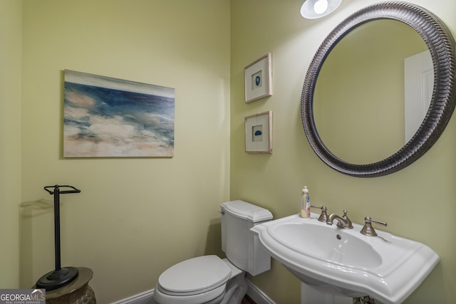 half bath with a sink, baseboards, and toilet