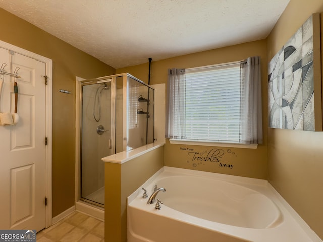 bathroom with a shower stall, a garden tub, and a textured ceiling