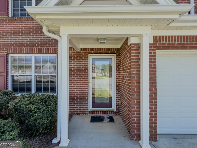 doorway to property featuring brick siding and an attached garage