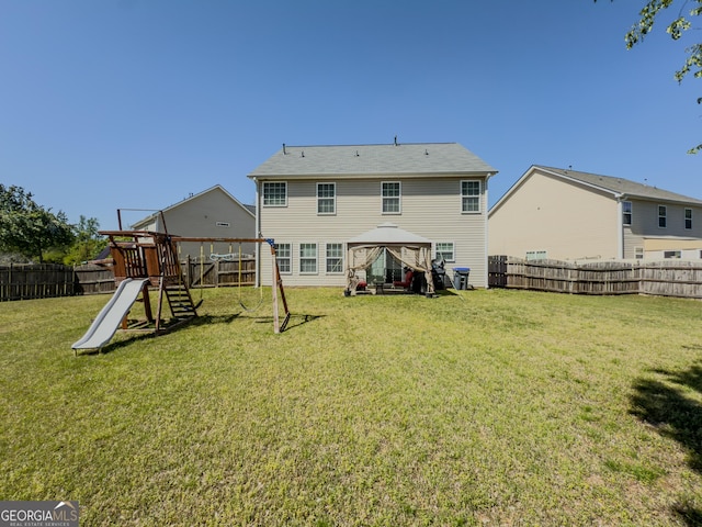 back of house featuring a fenced backyard, a gazebo, a yard, and a playground