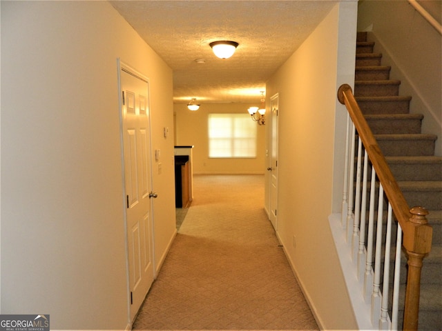 615 Magnolia Gardens Walk, Mcdonough, GA 30253 - hallway with a textured ceiling, baseboards, a chandelier, light colored carpet, and stairs