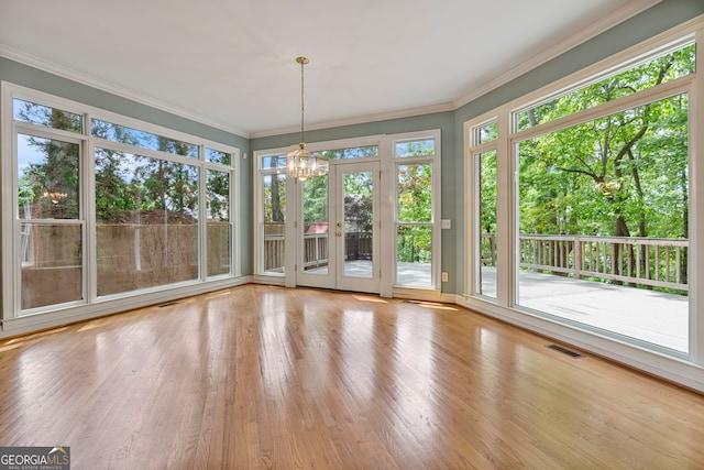 unfurnished sunroom featuring a chandelier, french doors, wood finished floors, visible vents, and ornamental molding
