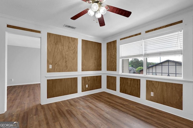 unfurnished room with ceiling fan, visible vents, ornamental molding, and wood finished floors