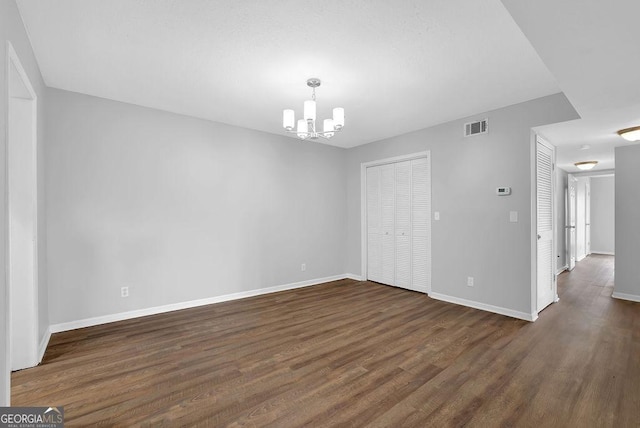 unfurnished dining area with an inviting chandelier, baseboards, dark wood finished floors, and visible vents