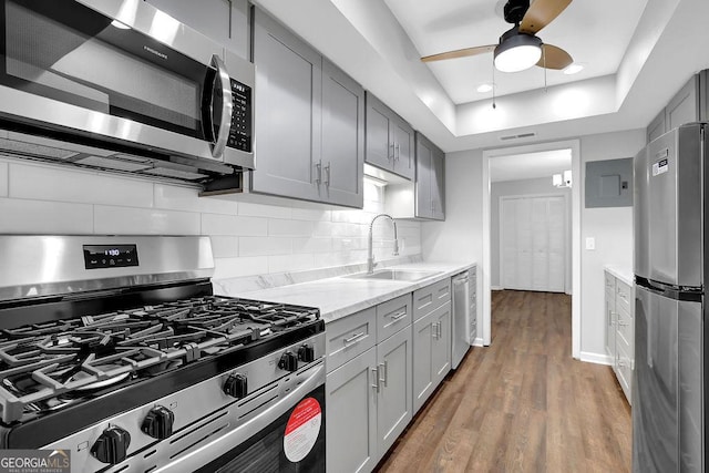 kitchen with a sink, gray cabinets, stainless steel appliances, and tasteful backsplash