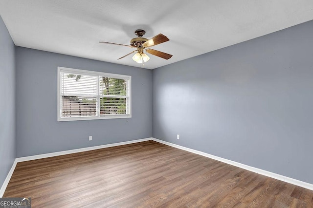 spare room featuring baseboards, ceiling fan, and wood finished floors