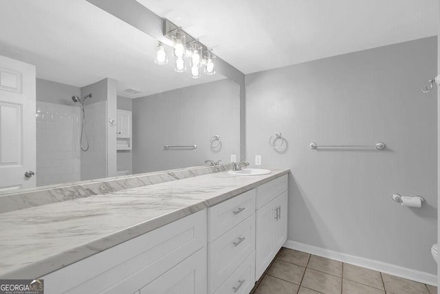 bathroom featuring vanity, toilet, tile patterned floors, baseboards, and tiled shower
