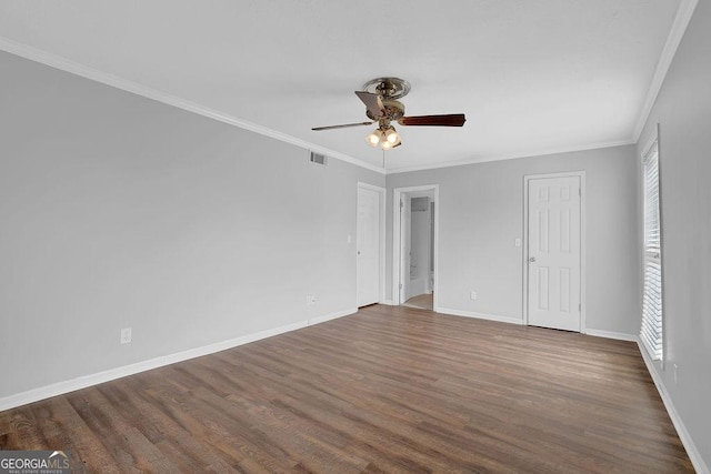 empty room with a ceiling fan, dark wood-style flooring, visible vents, crown molding, and baseboards