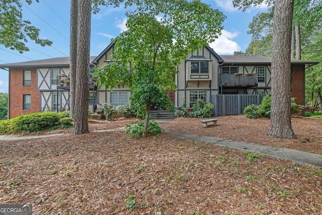 tudor-style house with brick siding, fence, and a balcony