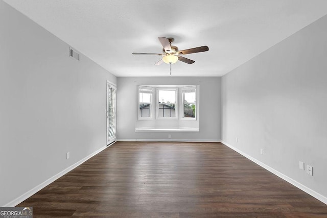 spare room featuring visible vents, dark wood finished floors, ceiling fan, and baseboards