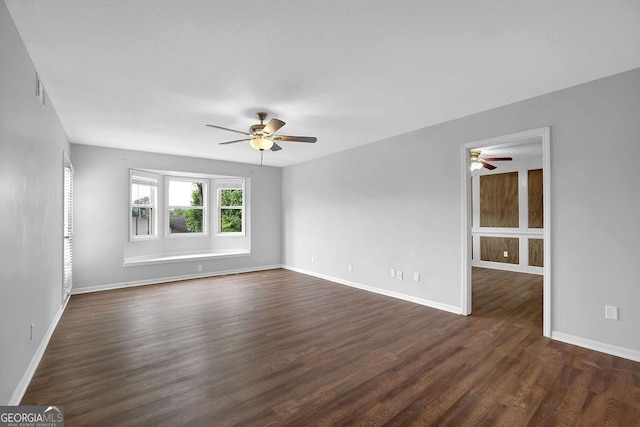 spare room with dark wood-style flooring, a ceiling fan, and baseboards