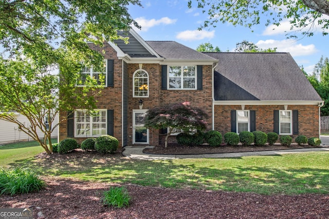 colonial-style house with brick siding, a front yard, and roof with shingles