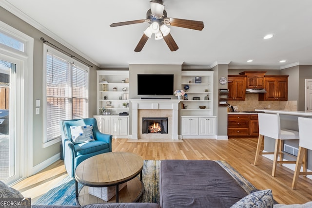1236 Brickton Dr NW, Atlanta, GA 30318 - living room featuring light wood-type flooring, crown molding, a ceiling fan, a fireplace with flush hearth, and baseboards