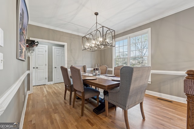 1236 Brickton Dr NW, Atlanta, GA 30318 - dining area featuring a chandelier, light wood finished floors, crown molding, and baseboards