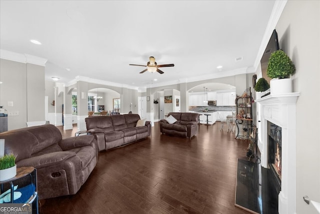 5950 Hidden Ridge Ct, Cumming, GA 30028 - living area with arched walkways, a ceiling fan, crown molding, dark wood-type flooring, and a glass covered fireplace