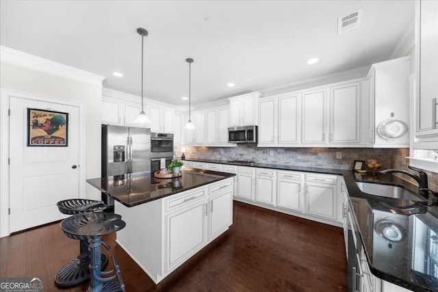 5950 Hidden Ridge Ct, Cumming, GA 30028 - kitchen featuring stainless steel appliances, white cabinets, a center island, tasteful backsplash, and ornamental molding
