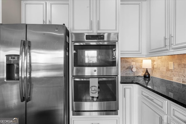 5950 Hidden Ridge Ct, Cumming, GA 30028 - kitchen with appliances with stainless steel finishes, dark stone counters, decorative backsplash, and white cabinetry