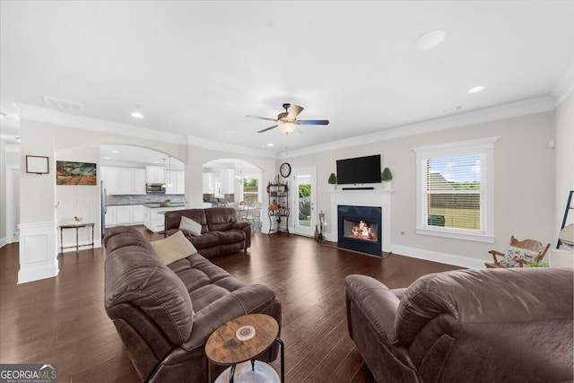 5950 Hidden Ridge Ct, Cumming, GA 30028 - living area with a ceiling fan, arched walkways, crown molding, dark wood-style floors, and a glass covered fireplace