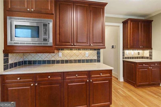 51 Sagemont Ct, Acworth, GA 30101 - kitchen featuring stainless steel microwave, backsplash, crown molding, and light wood-type flooring