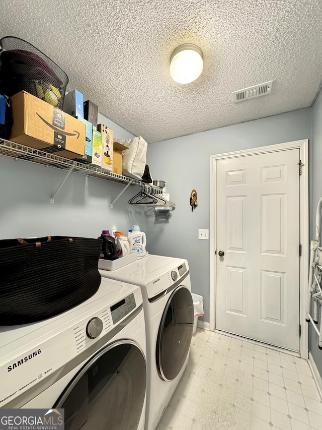 laundry room featuring a textured ceiling, washer and clothes dryer, visible vents, light floors, and laundry area