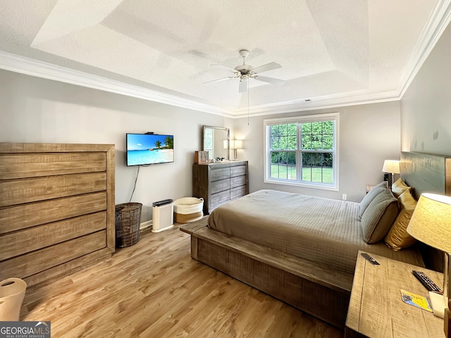 bedroom with light wood-style flooring, baseboards, a ceiling fan, crown molding, and a raised ceiling