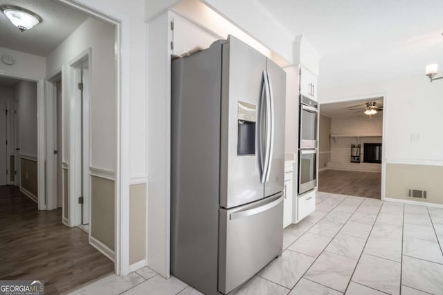 kitchen featuring white cabinets, marble finish floor, visible vents, a ceiling fan, and appliances with stainless steel finishes