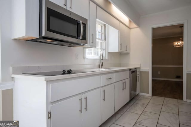 kitchen featuring marble finish floor, stainless steel appliances, light countertops, a sink, and white cabinetry
