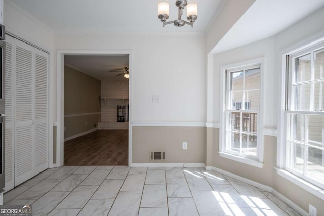 unfurnished dining area featuring visible vents, marble finish floor, a wealth of natural light, and ceiling fan with notable chandelier
