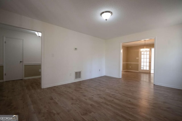 spare room featuring wood finished floors, visible vents, and baseboards