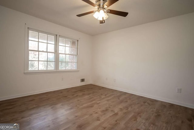 empty room featuring wood finished floors, visible vents, baseboards, and ceiling fan