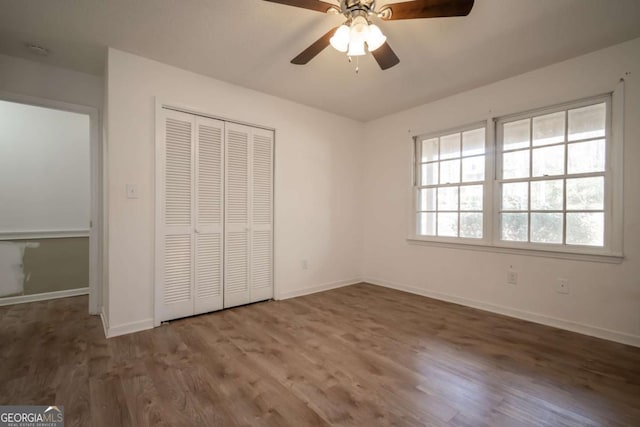 unfurnished bedroom featuring baseboards, a ceiling fan, wood finished floors, and a closet