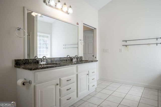 bathroom featuring tile patterned flooring, baseboards, a sink, and double vanity
