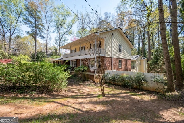 rear view of property featuring covered porch, a balcony, and brick siding
