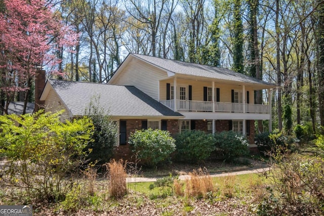view of front of property featuring a shingled roof and a balcony