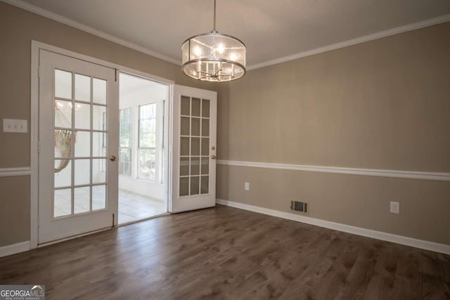 unfurnished dining area featuring baseboards, visible vents, a chandelier, wood finished floors, and ornamental molding
