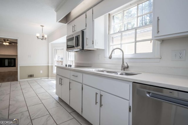 kitchen with plenty of natural light, marble finish floor, light countertops, a sink, and appliances with stainless steel finishes