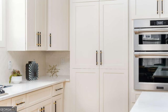 156 Martha Ave NE, Atlanta, GA 30317 - kitchen featuring multiple ovens, light countertops, decorative backsplash, and white cabinetry