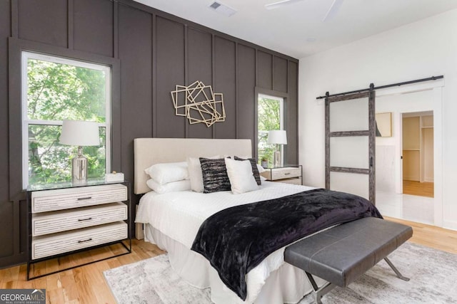 156 Martha Ave NE, Atlanta, GA 30317 - bedroom featuring a barn door, light wood-style flooring, and a ceiling fan