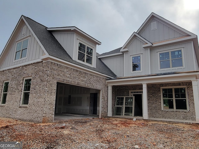 view of front of house with board and batten siding, a shingled roof, brick siding, and a garage