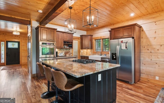 kitchen featuring appliances with stainless steel finishes, wood ceiling, light wood-style floors, a sink, and light stone counters