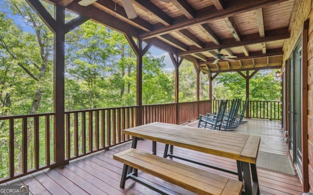 wooden terrace featuring a ceiling fan and view of wooded area